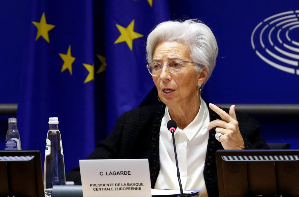 Egy fehér hajú nő, Christine Lagarde, mikrofon előtt ül egy konferencián, háttérben EU zászlókkal és a Parlament logójával.
