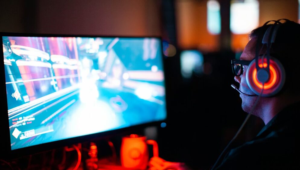 Játékos számítógépes játékot játszik, headsettel és monitor előtt